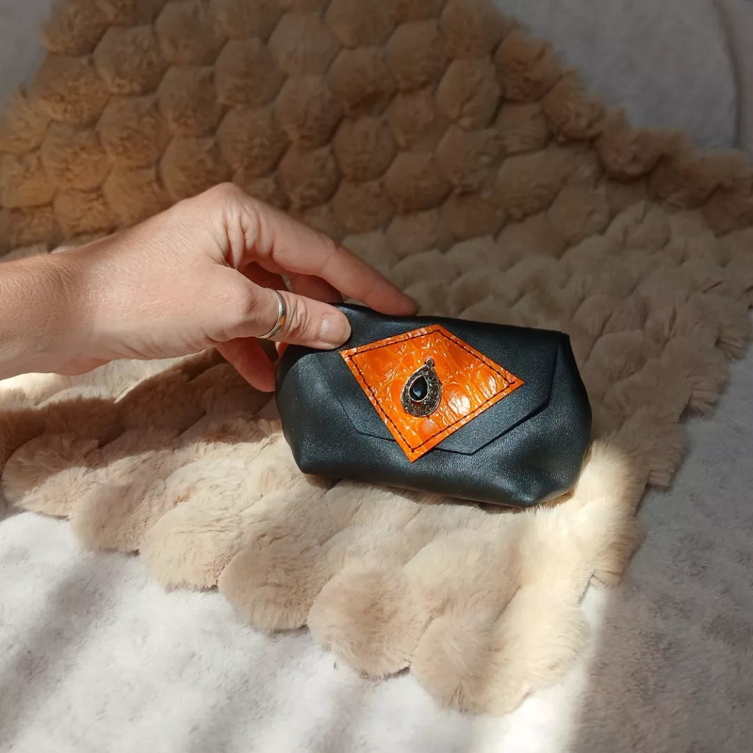 Porte-monnaie Rock n' Glow, réalisé avec des chutes de cuir noires et oranges, et orné d'une boucle d'oreille de seconde main.